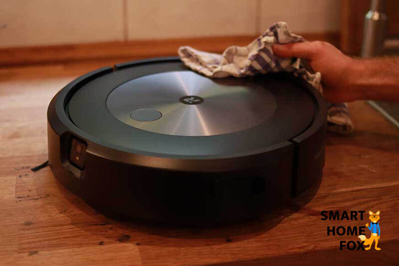 An iRobot Roomba vacuum robot is dusted with a cloth.